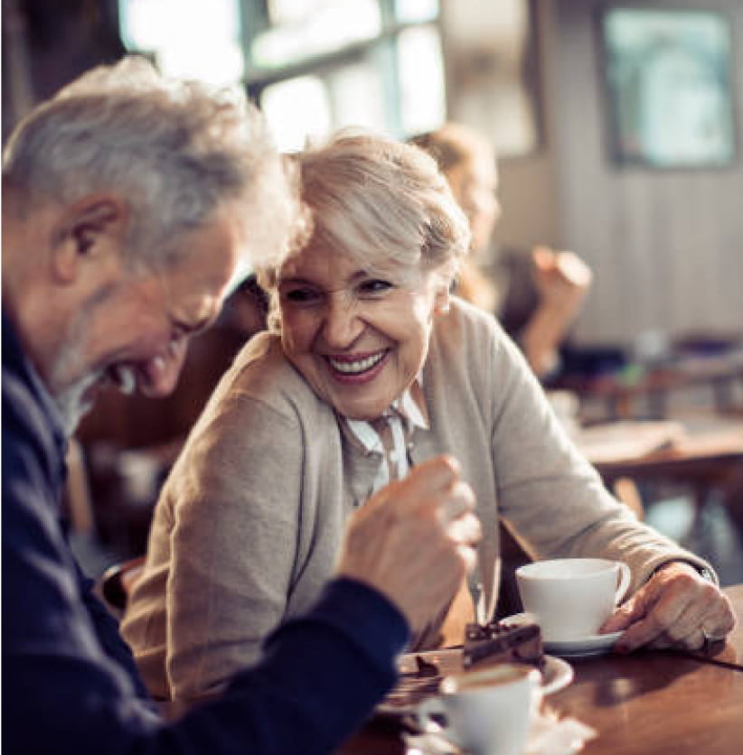 Two senior people laughing while enjoying a coffee